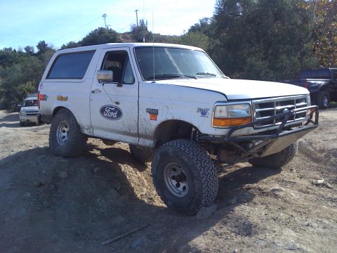 1995 Ford Bronco - A white Ford Bronco is shown from a 3/4 front angle on an off-road trail.