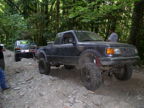 1993 Ford Bronco - A lifted Ford Ranger navigates a rocky off-road trail with another vehicle following.