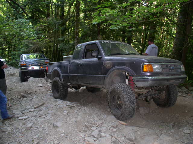Dusty purple Ford Ranger extended cab on a lifted solid-axle front end on a rocky trail