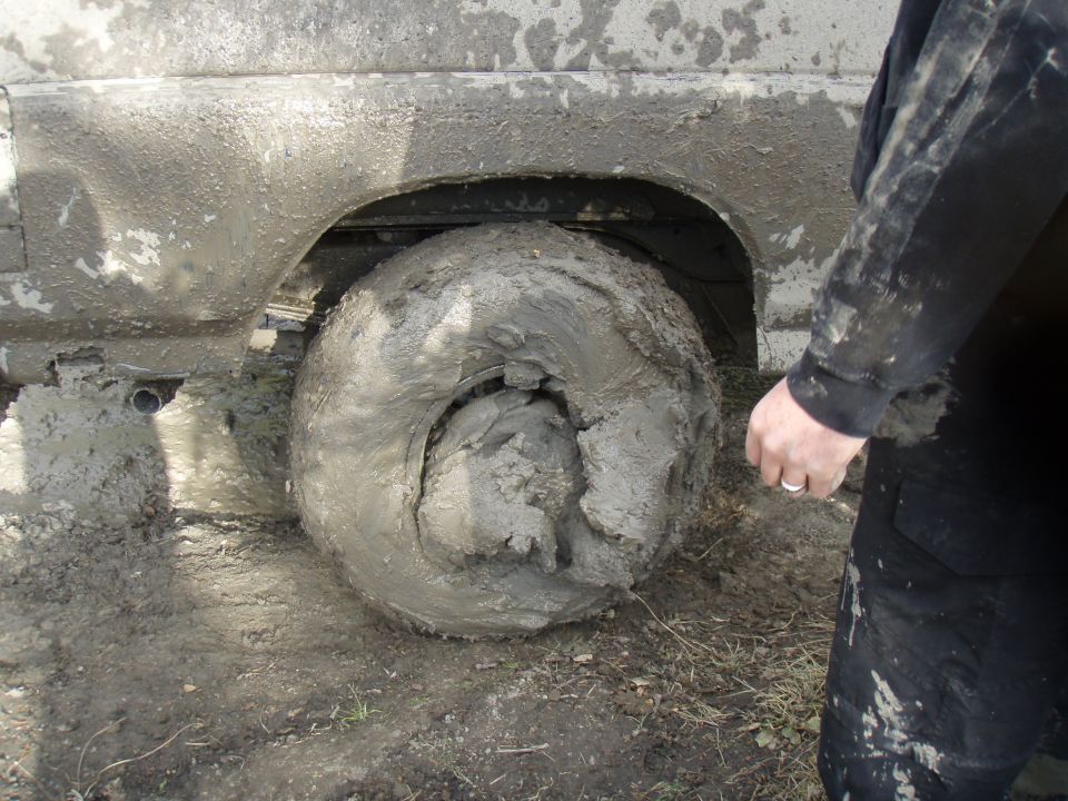 Mud-caked tire and fender of a vehicle stuck in the mud