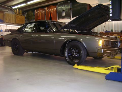 1979 Chevrolet Camaro - A modified 1977 Chevrolet sedan is shown in a garage with its hood up.
