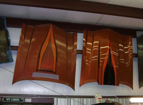 1979 Chevrolet Camaro - Two aftermarket car hoods are displayed, one with stripes and a vent, possibly for a 1979 Camaro.
