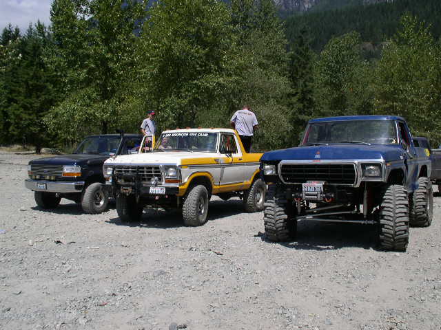 Three lifted Ford 4x4 Broncos parked on gravel at a mountain trailhead