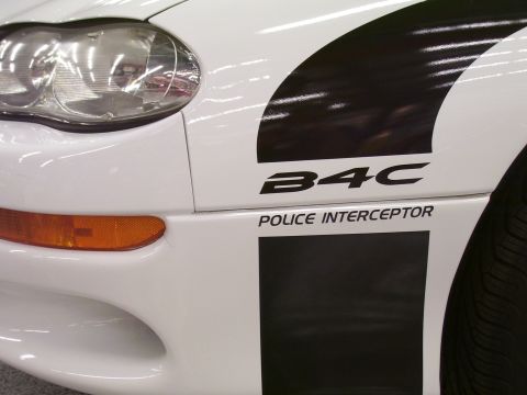 1979 Chevrolet Camaro - Close-up of a white police car's front fender and door, showing B4C Police Interceptor markings.