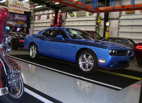 1979 Chevrolet Camaro - A blue Dodge Challenger is parked in a garage with other vehicles and memorabilia visible.