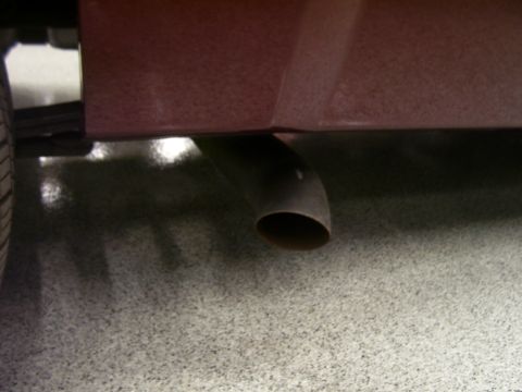 1979 Chevrolet Camaro - Close-up of a vehicle's exhaust pipe, with a portion of the body and tire visible.