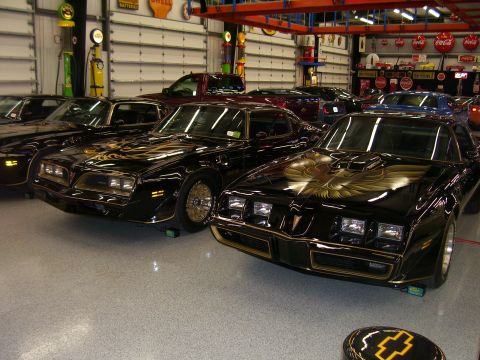 1979 Chevrolet Camaro - Multiple black Pontiac Firebird Trans Ams with gold bird decals are parked in a garage.