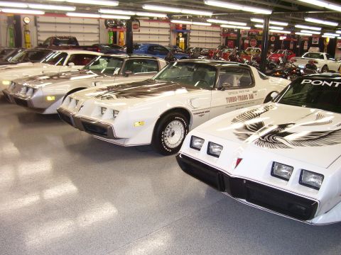 1979 Chevrolet Camaro - Several white Pontiac Trans Ams are lined up in a garage, some with black bird decals on their hoods.
