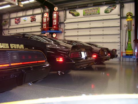 1979 Chevrolet Camaro - Multiple Pontiac Trans Am cars are lined up in a garage, vintage gas pumps and signage.
