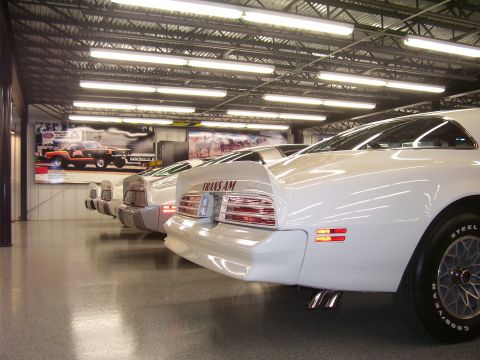 1979 Chevrolet Camaro - Several white Pontiac Trans Ams are parked in a showroom, with one prominently displaying its model name on the spoiler.