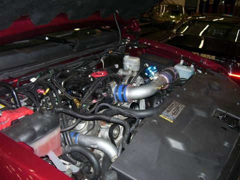 1979 Chevrolet Camaro - Engine bay modifications are visible on a red vehicle, with a second car in the background.
