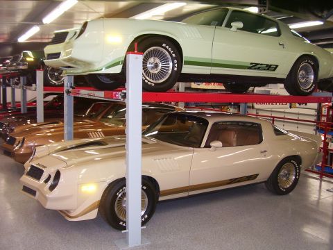 1979 Chevrolet Camaro - Two Chevrolet Camaros, a cream Z28 in the foreground and a green Z28 above, are displayed on car lifts.
