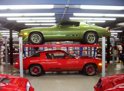 1979 Chevrolet Camaro - Two Chevrolet Camaro Z28s, one green and one red, are parked on a two-post car lift in a garage.