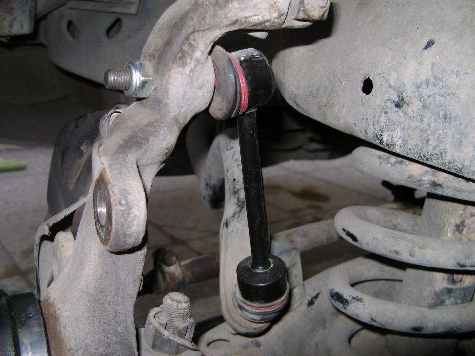 New black sway bar end link installed on dusty front suspension near coil spring