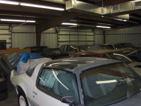 1970 Chevrolet Camaro - A white coupe with a black roof is parked inside a garage, surrounded by other vehicles, with a price tag visible on the window.