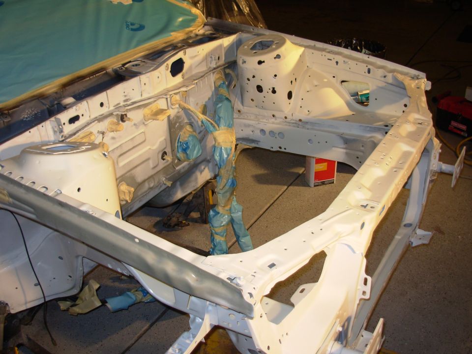 car frame with blue tape and plastic sheeting, looks like it's being prepped for paint