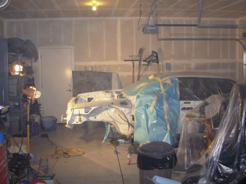1991 Ford Taurus - Car body undergoing work in a garage, with parts covered in plastic sheeting.