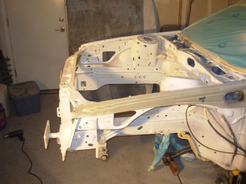 1991 Ford Taurus - Front end of a car chassis undergoing restoration work, stripped to the bare metal.