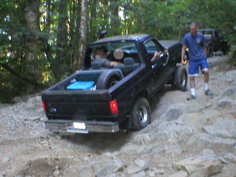 1978 Ford Bronco - Black pickup truck navigates a challenging rocky trail with a second vehicle in the distance.