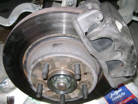 1998 Ford Crown Victoria - Close-up view of a vehicle's front wheel hub and brake caliper, showing mechanical components.