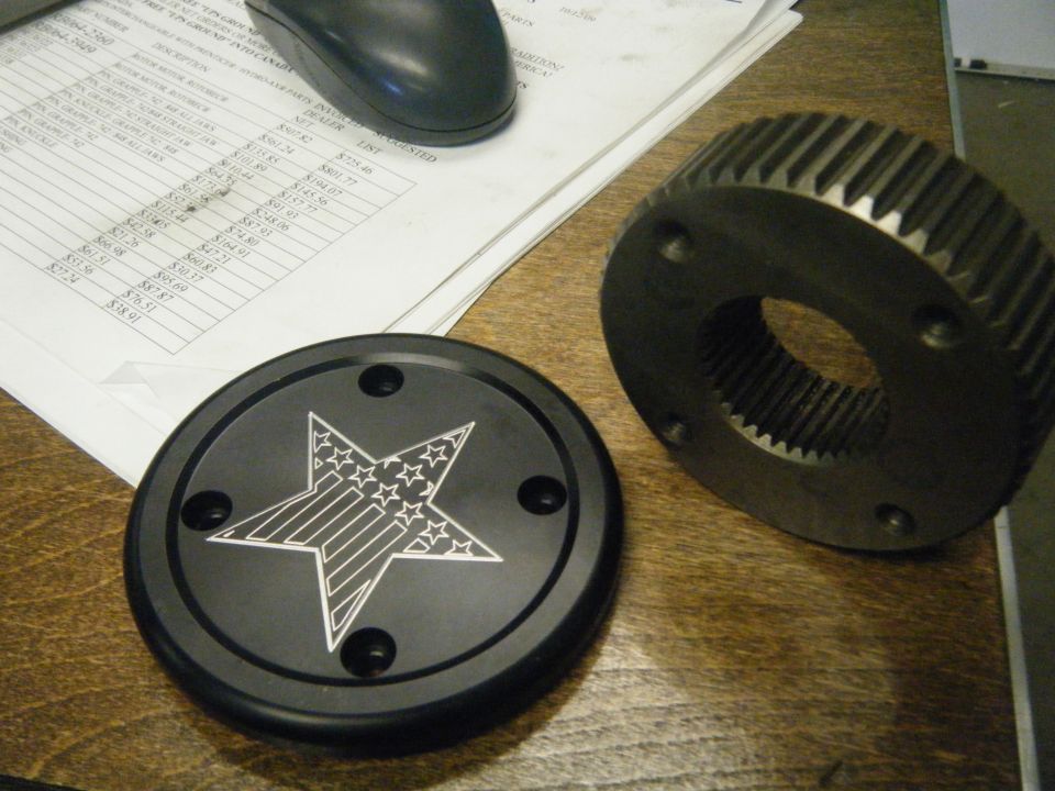 Black hubcap with American flag star and a metal gear on a desk with papers