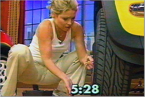 1993 Ford Bronco - A woman is seen working on a car tire, with a yellow car body visible on the right.