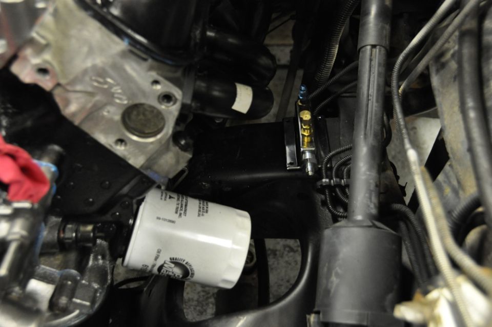 Engine oil filter screwed onto engine block with various hoses and metal components visible