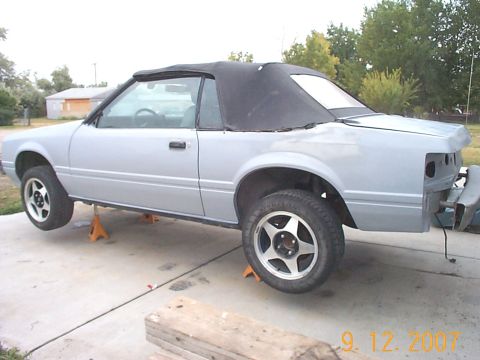 1984 Ford Mustang - Ford Mustang convertible undergoing work, missing its rear bumper.