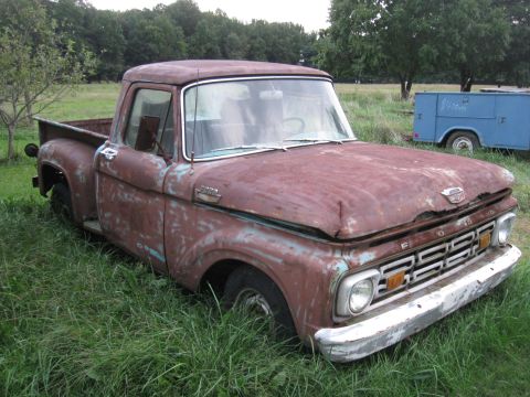 1966 Ford F-250 - This weathered 1966 Ford F-250 pickup truck sits in a grassy field, showing its age with extensive rust.