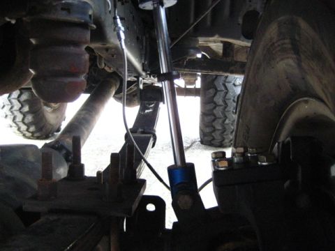 1989 Ford Bronco - A close-up view of the undercarriage reveals leaf springs and a shock absorber, with the Supermotors.net logo visible at the bottom.