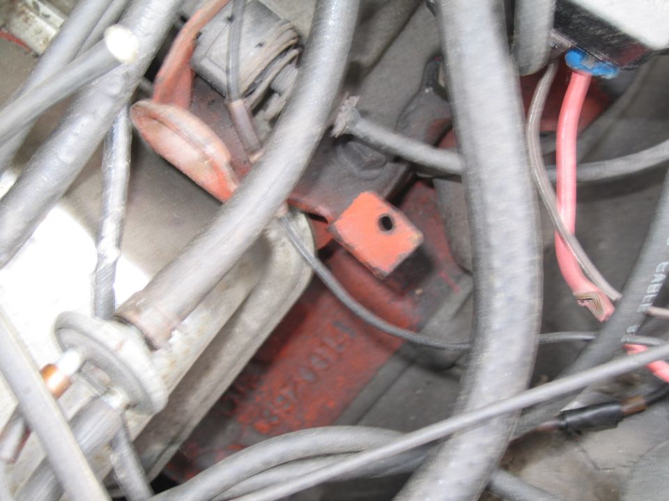 Engine compartment with hoses, wires, and a red-painted block with visible numbers