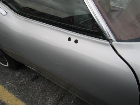 1991 Ford LTD Crown Victoria - Close-up view of a silver car's side door, showing two circular trim pieces near the window.