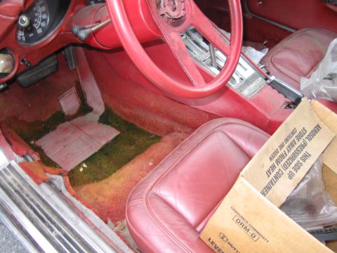1991 Ford LTD Crown Victoria - The interior of a car shows significant wear and tear, with stained carpeting and a box of supplies.