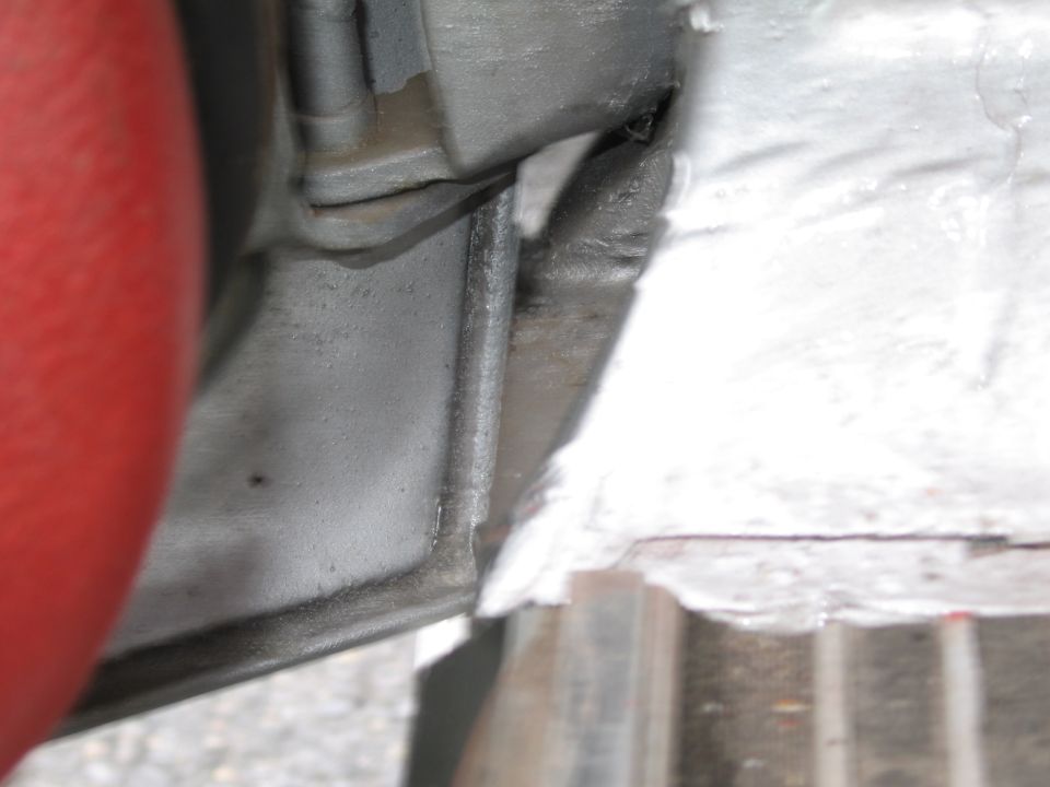 Close-up of a red hose next to a metal bracket on a vehicle's undercarriage