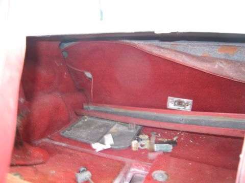 1991 Ford LTD Crown Victoria - The interior of a vehicle's trunk space is visible, red carpeting and various components.