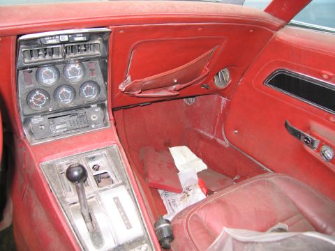 1991 Ford LTD Crown Victoria - The interior of a classic car shows red upholstery, a dashboard with multiple gauges, and a center console with a gear shift lever.