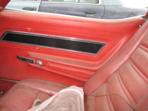 1991 Ford LTD Crown Victoria - Interior view of a red door panel and seat, with another vehicle partially visible outside.