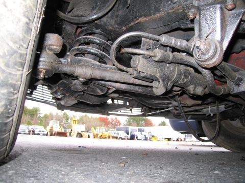 1991 Ford LTD Crown Victoria - A view of the undercarriage of a vehicle, with other vehicles and equipment in the background.
