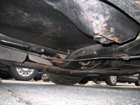1991 Ford LTD Crown Victoria - The underside of a vehicle is captured, revealing suspension and exhaust systems. Other vehicles are visible in the background.