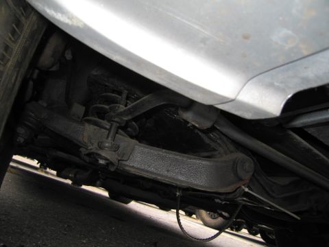 1991 Ford LTD Crown Victoria - The undercarriage of a vehicle, including suspension parts and a tire, with another vehicle in the background.