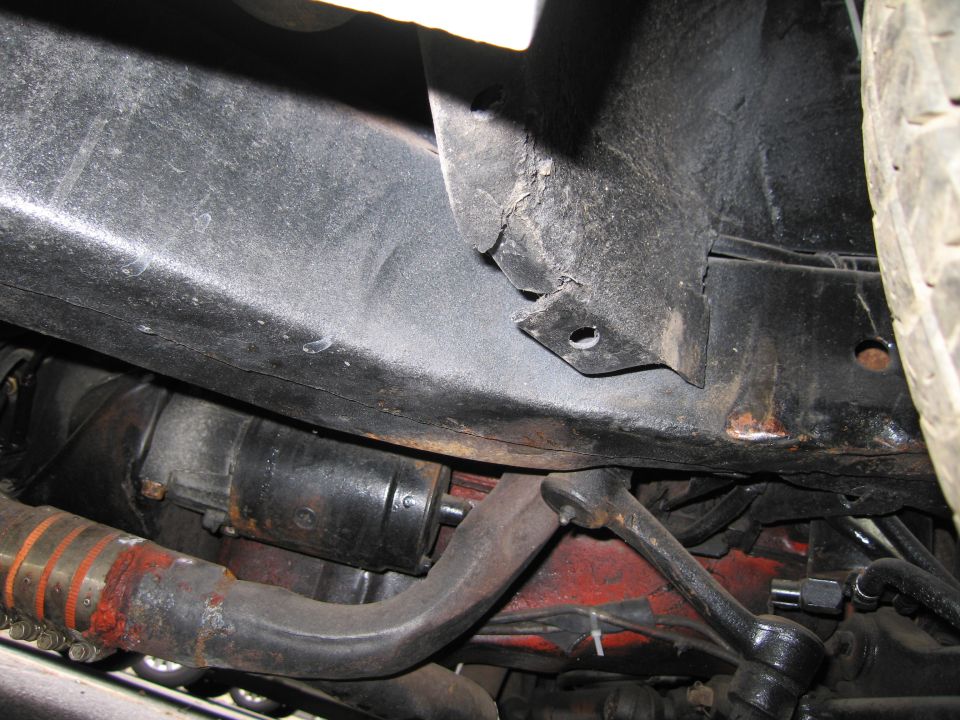 Undercarriage of a vehicle showing a starter motor, exhaust pipe, and suspension components
