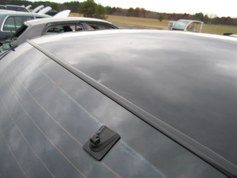 1991 Ford LTD Crown Victoria - Close-up of a car's rear window and antenna base, with other vehicles visible in the background.