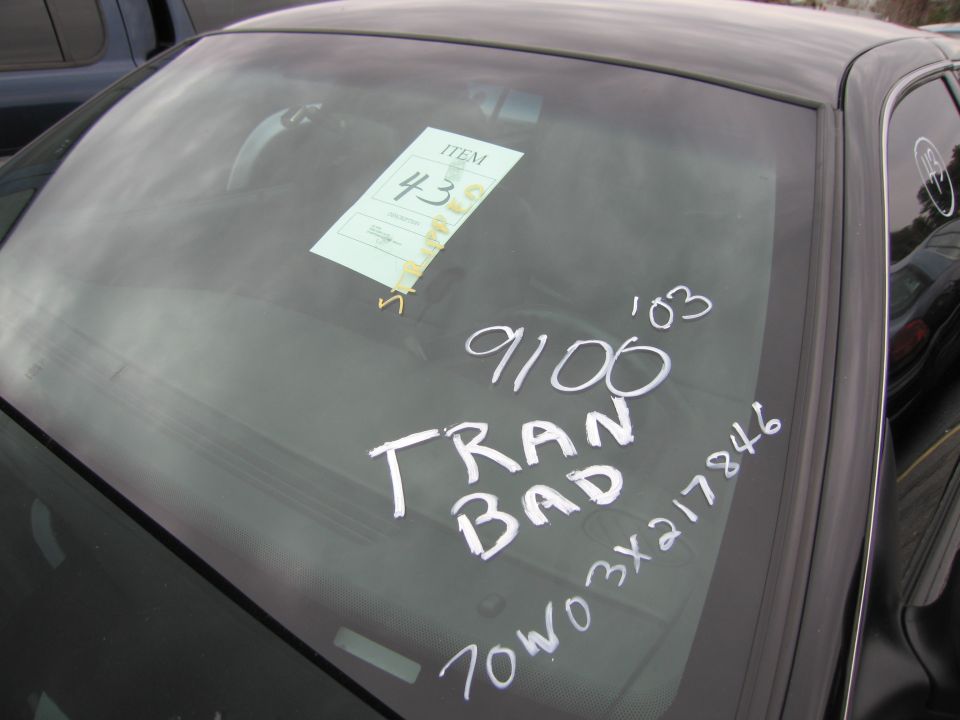 Car windshield with a paper tag and white writing that says 'TRAN BAD' and some numbers