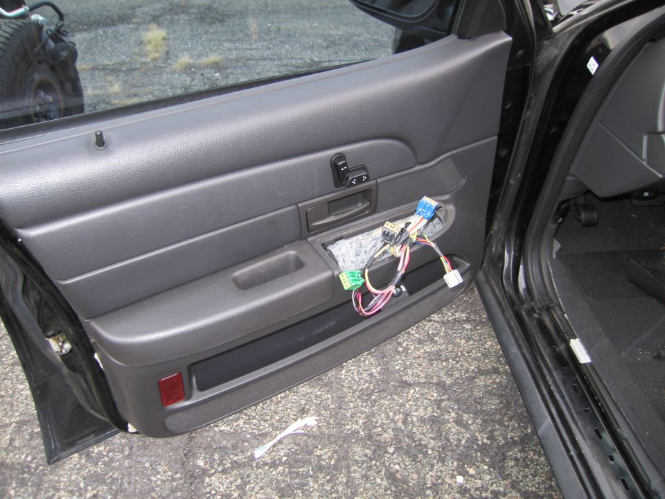 Black car door panel with removed trim exposing wires and connectors