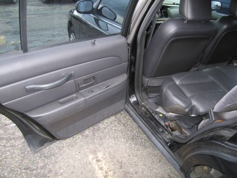 1991 Ford LTD Crown Victoria - The interior of a black sedan is visible, with the driver's side door open, revealing the door panel and rear seating area.