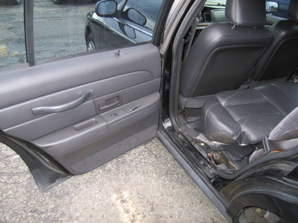 Interior view of a black car showing the driver's side door panel and rear seats