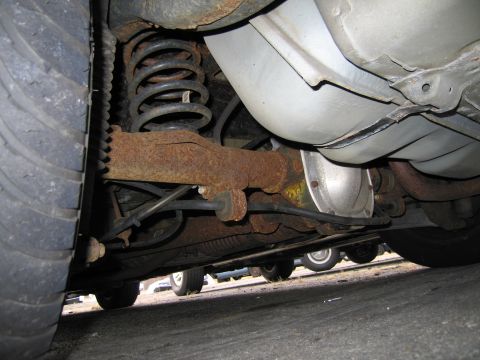 1991 Ford LTD Crown Victoria - Close-up of a vehicle's rear axle and suspension system, with other cars in the background.