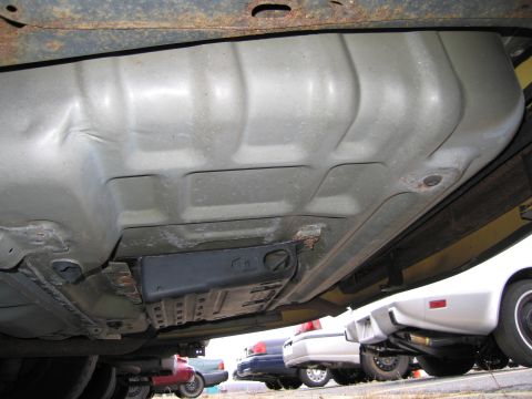 1991 Ford LTD Crown Victoria - The undercarriage of a vehicle is visible, with other cars parked in the background.