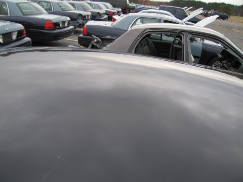 1991 Ford LTD Crown Victoria - Interior view of a dark sedan with open doors, parked in a lot with other vehicles.