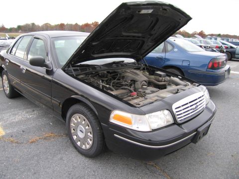 1991 Ford LTD Crown Victoria - A black Ford Crown Victoria is parked with its hood open, revealing the engine compartment. Another vehicle is visible in the background.